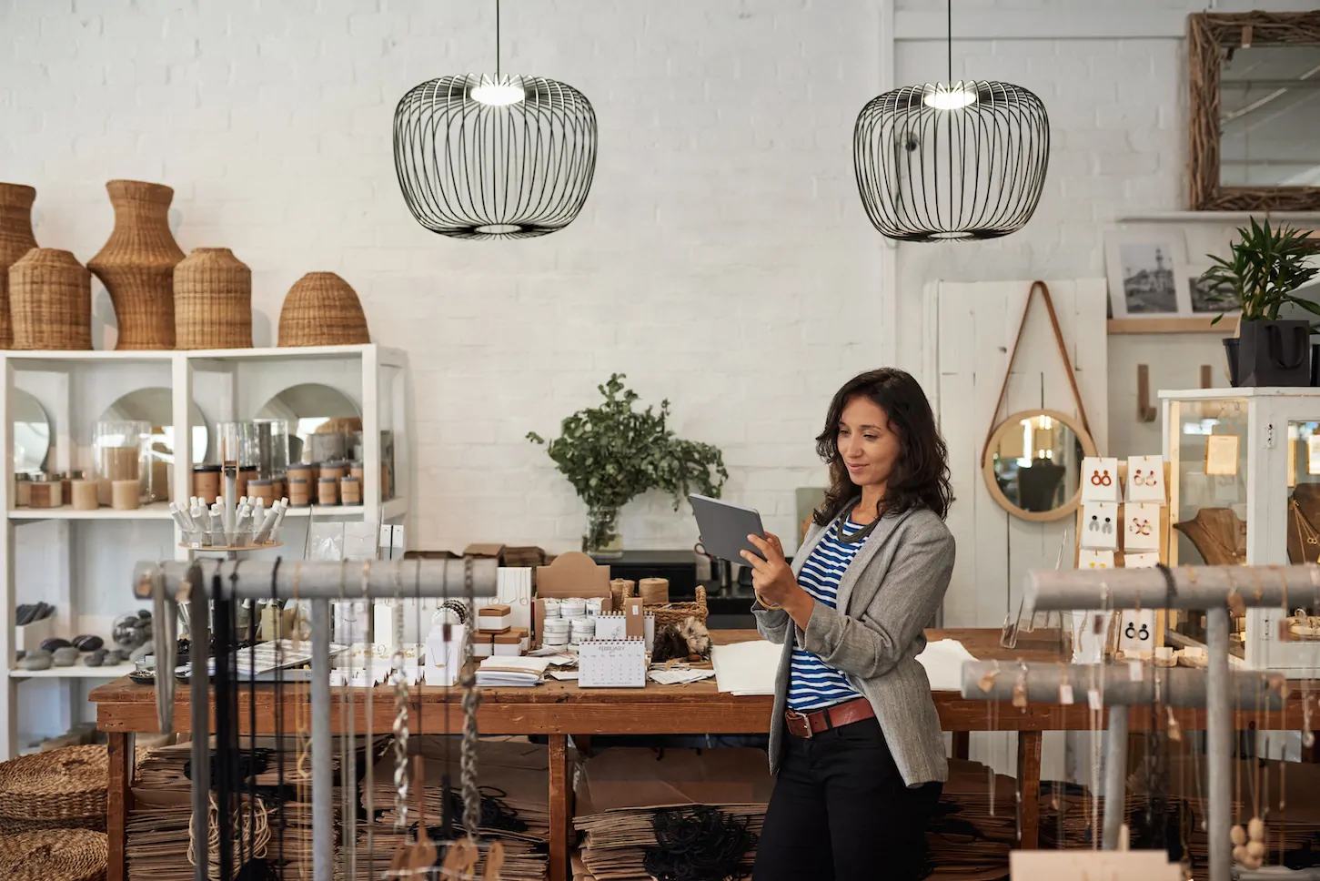 Young woman using a digital tablet while standing by a display in her stylish boutique