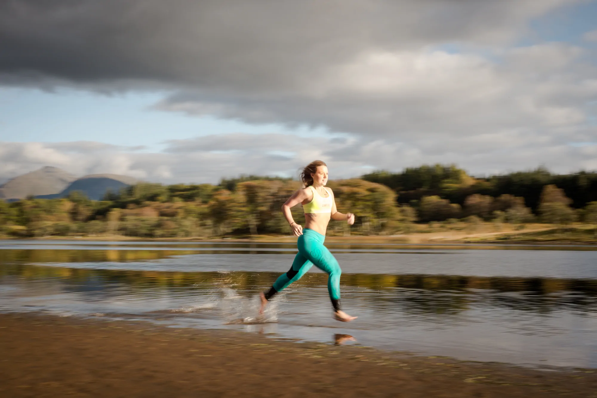 A female wearing sportswear running across the shore on a cloudy day