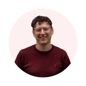 A male member of staff with a pink background
