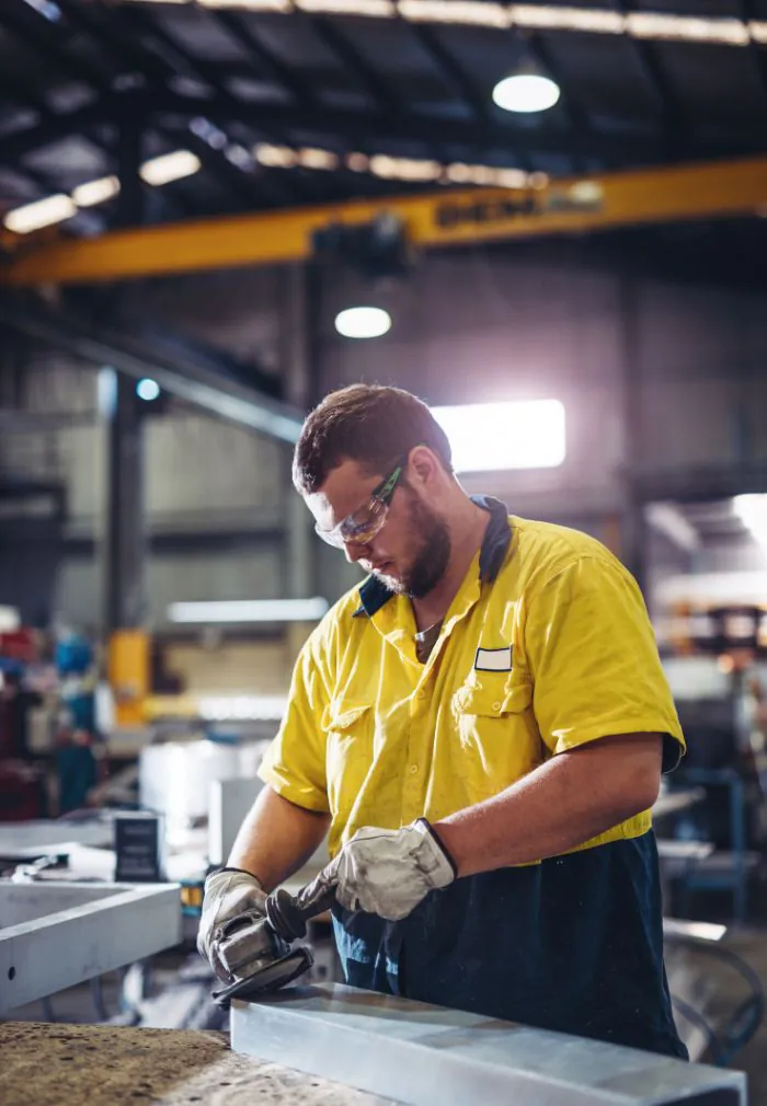 Fractional CFO for manufacturing industry image. Man working in a factory in a yellow shirt.